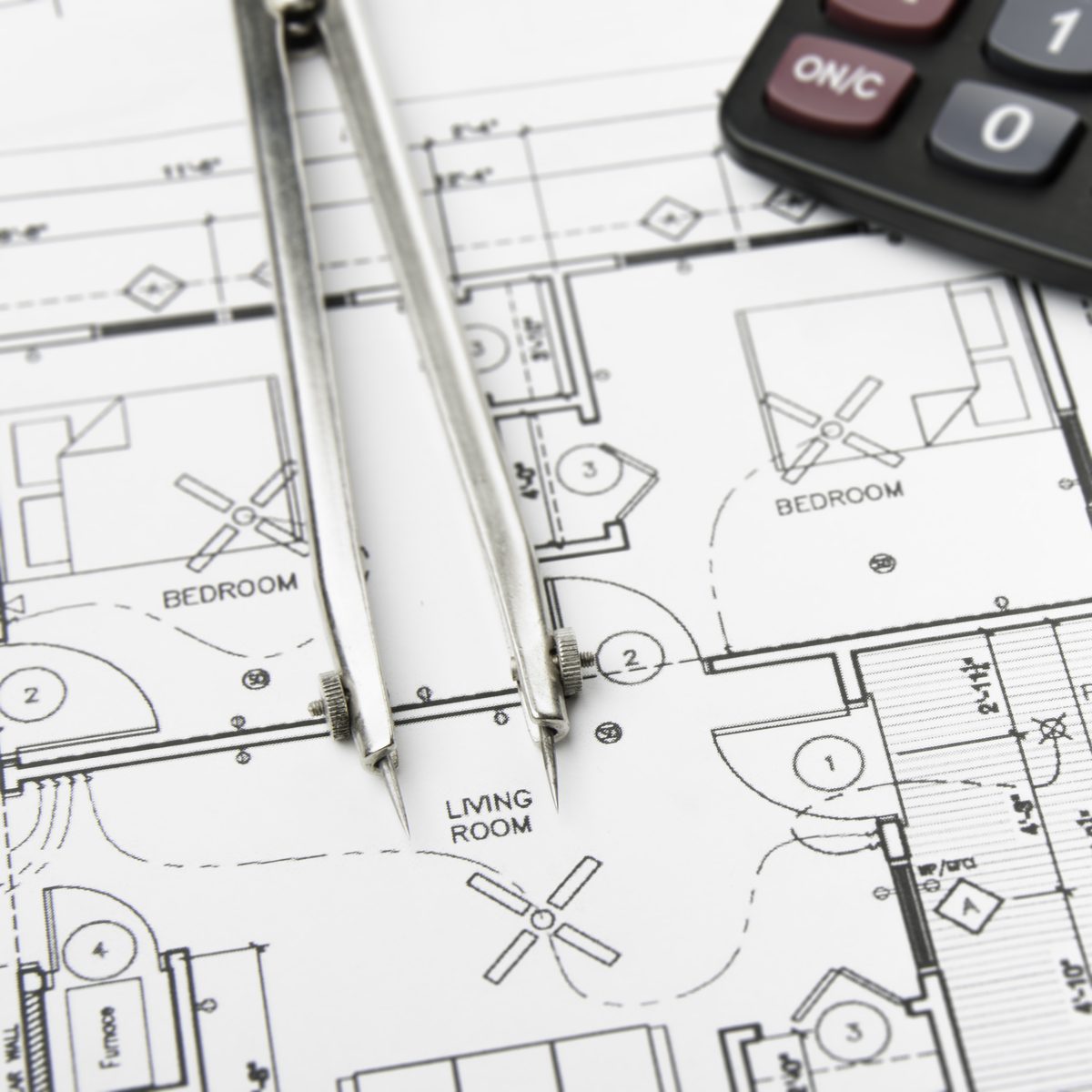 Plano arquitectónico con compás y calculadora